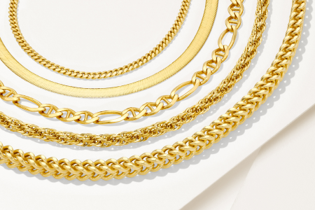 a variety of gold chain necklaces layered on a tabletop